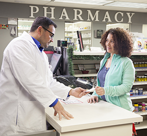 Pharmacist talking with woman at pharmacy counter